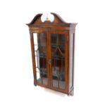 A Reprodux mahogany wall hanging display cabinet, the break arch pediment over two doors opening