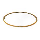 A Victorian brass oval framed wall mirror, inset bevelled glass, with embossed shield and ribbon