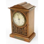 An Edwardian oak cased mantel clock, with scroll leaf and flower design with brass plaque to