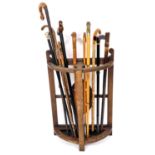An early 20thC demi lune stick stand, with lead liner and a quantity of walking sticks, to include