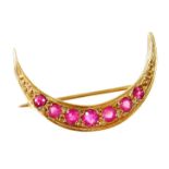 A 9ct gold garnet set crescent brooch, the crescent moon set with seven graduated stones, on a
