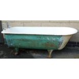 A vintage cast iron and enamel bath, of oval form on heavy cast hairy paw feet, with two taps and