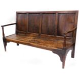 An 18thC elm, oak and pine settle, the back formed possibly with a coffer top, with scroll carved