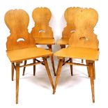 A set of four 20thC carved oak chairs, each with shield backs and pierced handles to the splats,