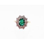 An 18ct gold emerald and diamond cluster ring, with oval cut emerald 8.6mm x 6.6mm x 3.8mm,