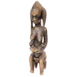 A 19thC heavily carved African tribal figure of a seated lady, with flowing hair on a stool, 98cm