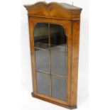 A George I style yew hanging corner cabinet, with moulded cornice on six section astragal glazed