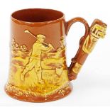 A 20thC Dartmouth pottery golfing tankard, with golf bag handle, the body depicting raised golfing