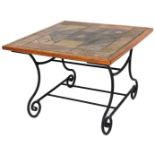 A 20thC tile topped coffee table, on a wrought iron scroll stand, with newspaper rack beneath,