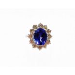 A tanzanite and diamond cluster ring, with oval cut AAA tanzanite, 4.95cts, in four claw setting,