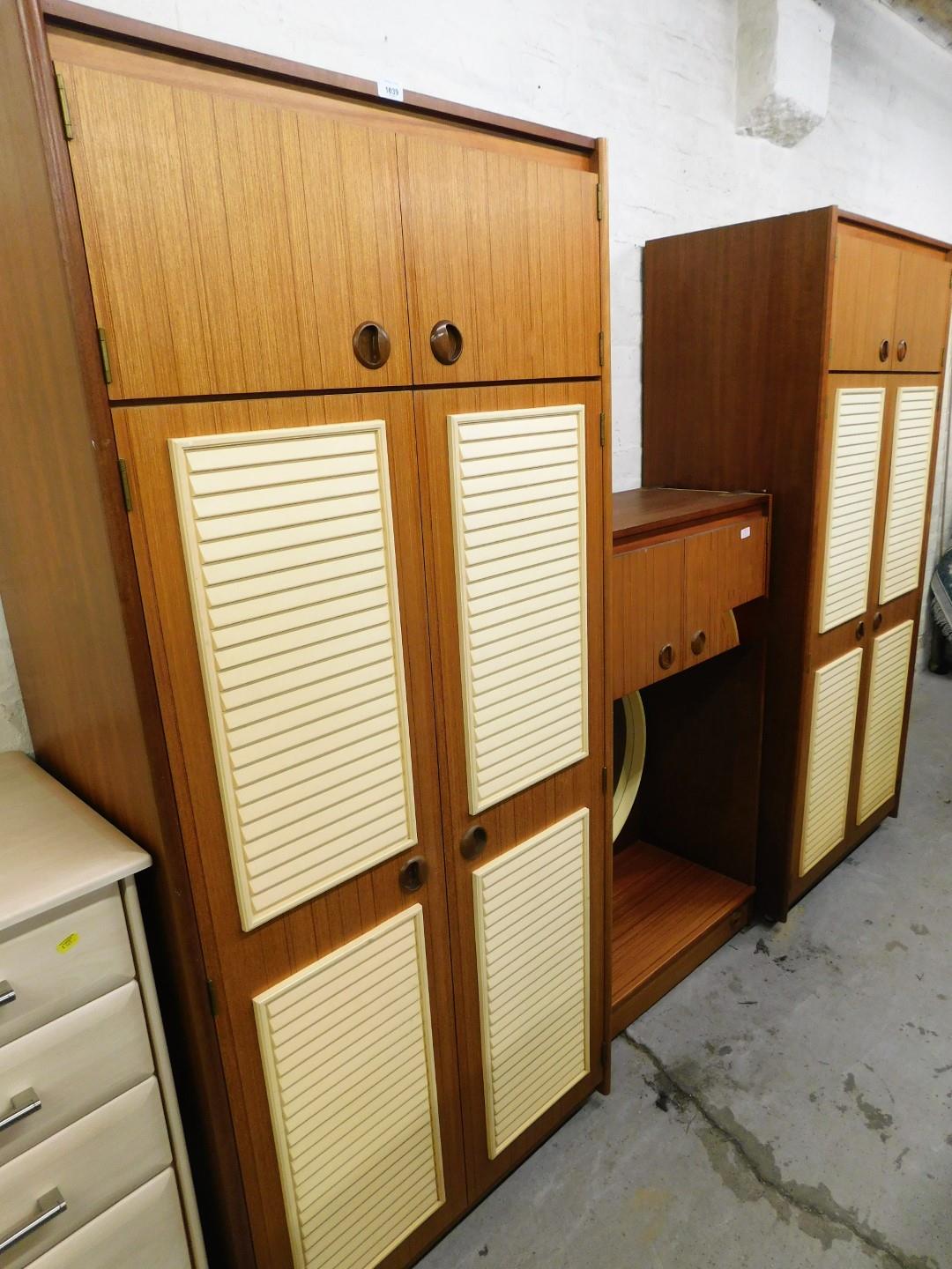 A teak 1970's style bedroom suite, comprising two two door wardrobes, and a wall mountable