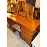 A large pine dressing table, the top with four drawer section to each side, stool section to centre,