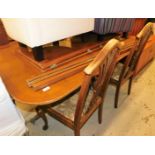 A yew veneered extending twin pedestal dining table and a matched set of four chairs, the table with