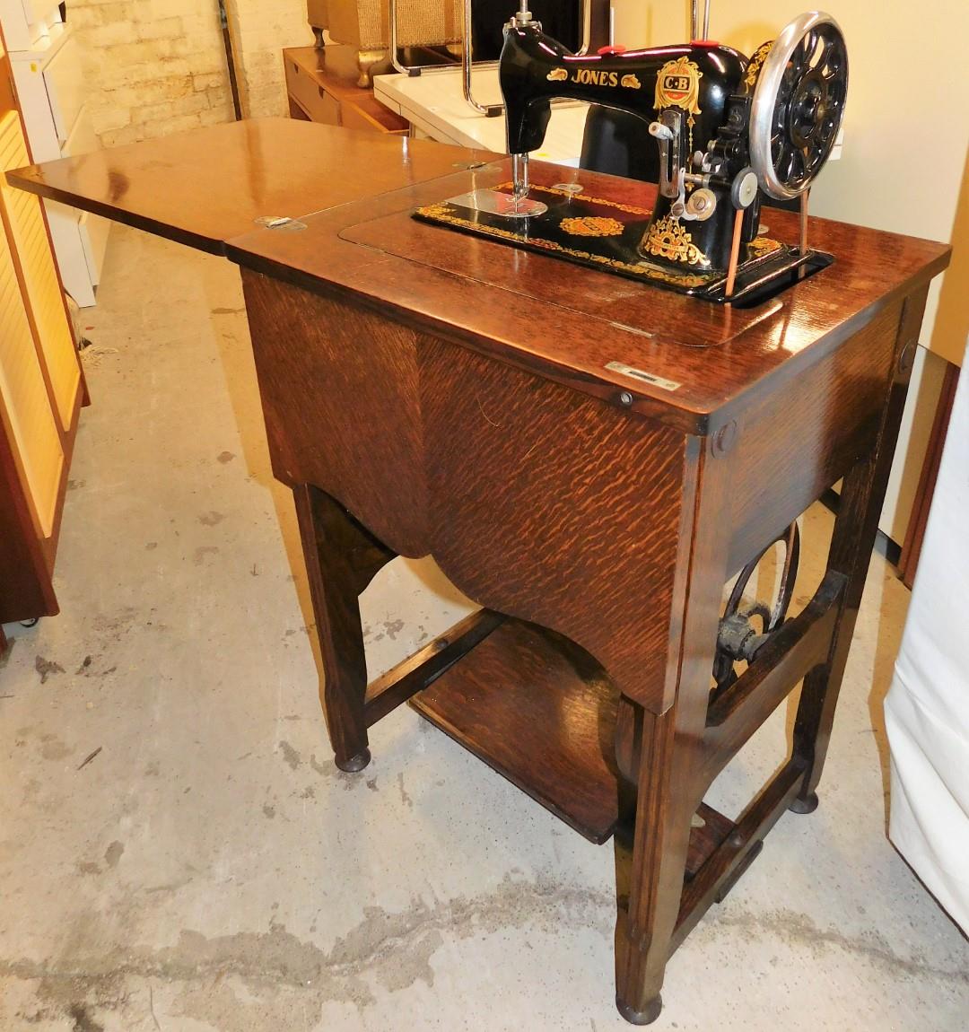 A Jones sewing machine in oak stand, enclosed in a mahogany tailors work stand, with compartment