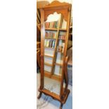 A pine framed cheval dressing mirror, the rectangular mirror plate with curved cornice on swing