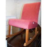 A beech framed rocking chair, the chair with pink upholstery and button finish, lacking arms.