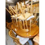A pine twin pedestal kitchen table, with a set of eight associated stick back kitchen chairs, 75cm