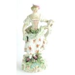 A late 18thC Derby porcelain lady, modelled holding flowers in her dress, on a flower encrusted