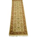 An Afghan runner, with a design of flowers, leaves, etc., on a dark beige ground with one wide