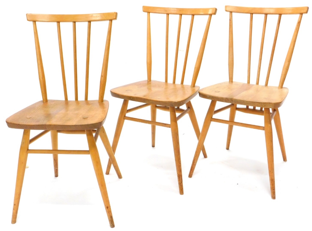 A set of three light coloured Ercol stick back chairs, each with a solid seat on turned tapering