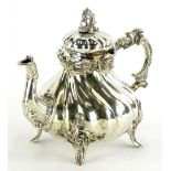 A continental white metal teapot, of rococo form with a pierced knop, scroll cast bands and a