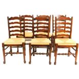 A set of six oak ladder back chairs, each with a rush seat on turned tapering legs.