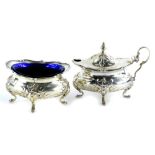 An Edwardian oval silver salt, decorated with shells, scrolls, etc., on four feet, with blue glass