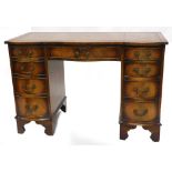 A mahogany kneehole desk, the top with a brown leather inset and a shaped front, above an