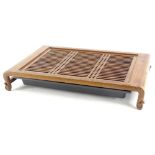 An oriental hardwood low stand, with a pierced lattice top and scroll carved feet, containing a drip
