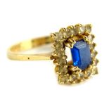 A dress ring, set with blue and white paste stones, in pierced raised basket setting, on a yellow