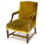A mahogany open armchair in George III style, upholstered in green velvet on chanelled legs.