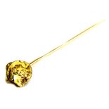 An Art Nouveau stick pin, with circular head depicting a maidens head, yellow metal, unmarked, 6cm