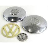 Two Volkswagen chrome plated wheel hub caps, 25.5cm diameter, a cream plastic VW sign and a silvered