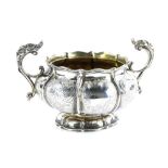 A George III silver two handled sugar bowl, of lobed form, engraved with scrolls etc., the handles