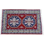 A Turkish type rug, with a design of two large latch hook medallions in mainly blue, maroon and