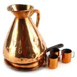 A late 19th/early 20thC copper flagon, a pan lid and three copper and brass measures.