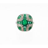 An Art Deco style emerald and diamond ring, with central oval cut emerald and further baguette cut