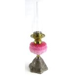 A Victorian cast metal and brass oil lamp, with a pink tinted moulded reservoir and a tapering base,