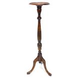 A mahogany torchere or plant stand, the circular dished top on a leaf carved turned column and