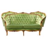 A continental beech three piece suite, with a moulded show frame, upholstered in green buttoned