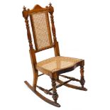 A Victorian walnut rocking side chair, with a caned back and seat and H stretcher.