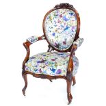A Victorian walnut showframe armchair, carved with flowers leaves etc., upholstered in vivid