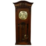 A 1920s mahogany wall clock, with a shaped cornice above a silvered dial and a glazed door.