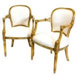 A pair of continental gilt open armchairs, each with a cream damask upholstered back and seat,