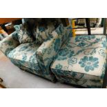 A large armchair and matching stool, upholstered in green and silver coloured floral fabric.