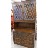 A dresser, the top with leaded glazed doors, the base with two drawers and two doors.