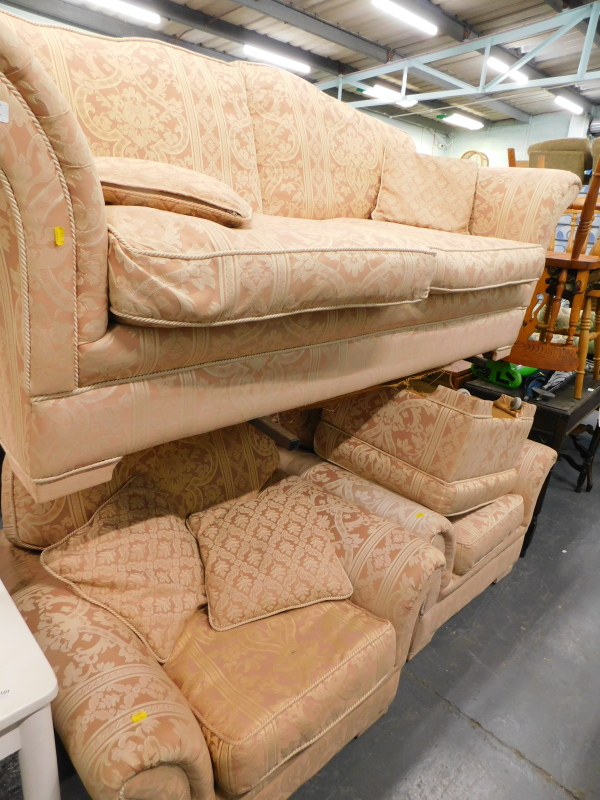 A two seater sofa, two armchairs and a foot stool, in pink floral fabric.