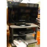 A Toshiba 32 inch LCD TV, a Samsung video recorder, and a stand with remotes.