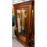 A modern cherry display cabinet, with fixed moulded top, raised above a glass panel door revealing