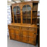 An Old Charm style oak display cabinet, with glazed doors, raised above two frieze drawers, and